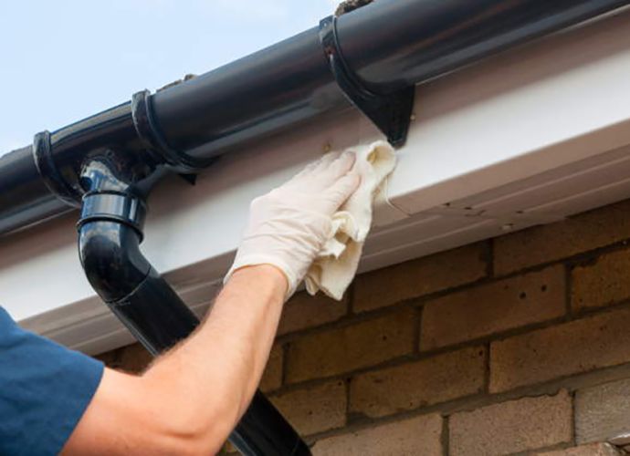 man cleaning a roof facia board